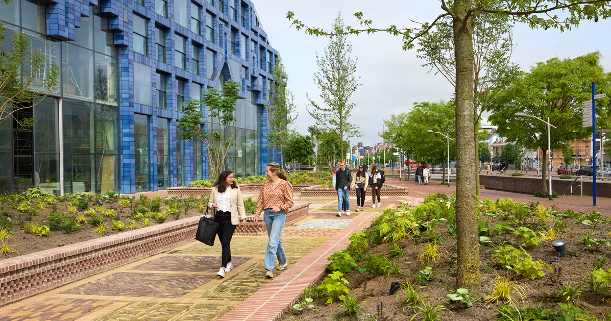 groep mensen, met twee dames voorop lopen door de tuin van delft